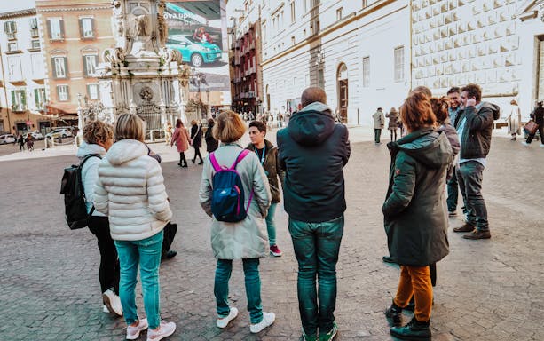 Group of tourists listening to a guide in Naples Old Town Centre.