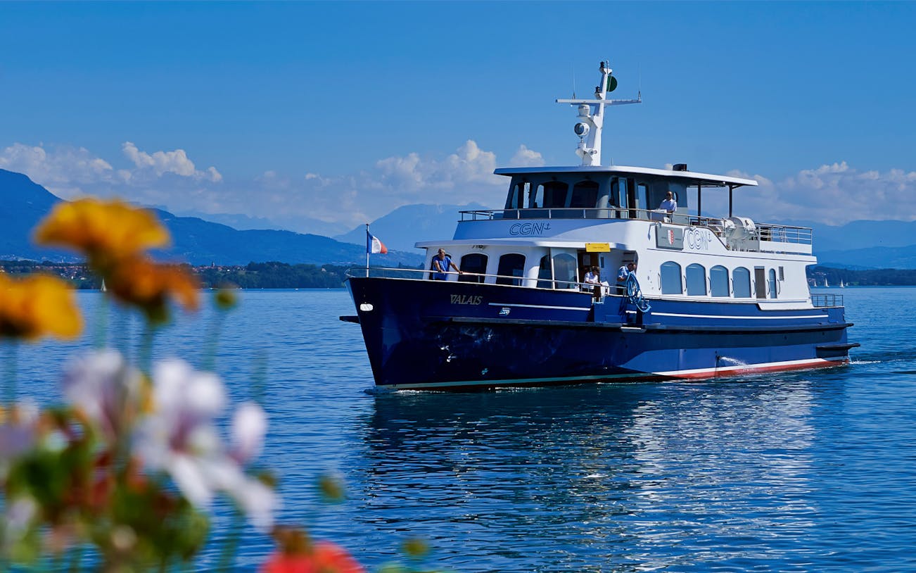 Cruise boat on Lake Geneva with mountains in the background.