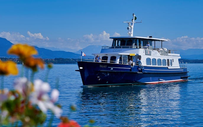 Cruise boat on Lake Geneva with mountains in the background.