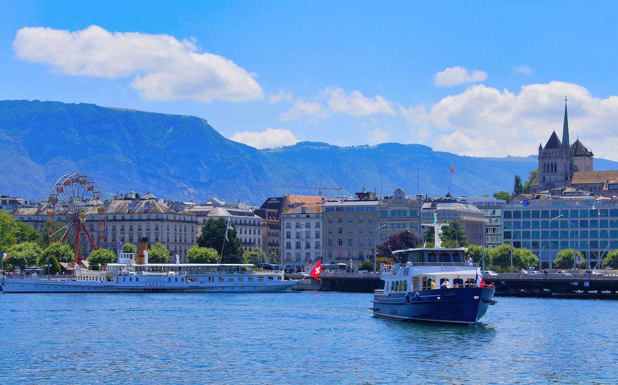 Lake Geneva cruise boat with cityscape and mountains in the background.