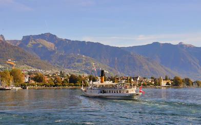 Cruise boat on Lake Geneva with Chillon Castle and Swiss Alps in the background.