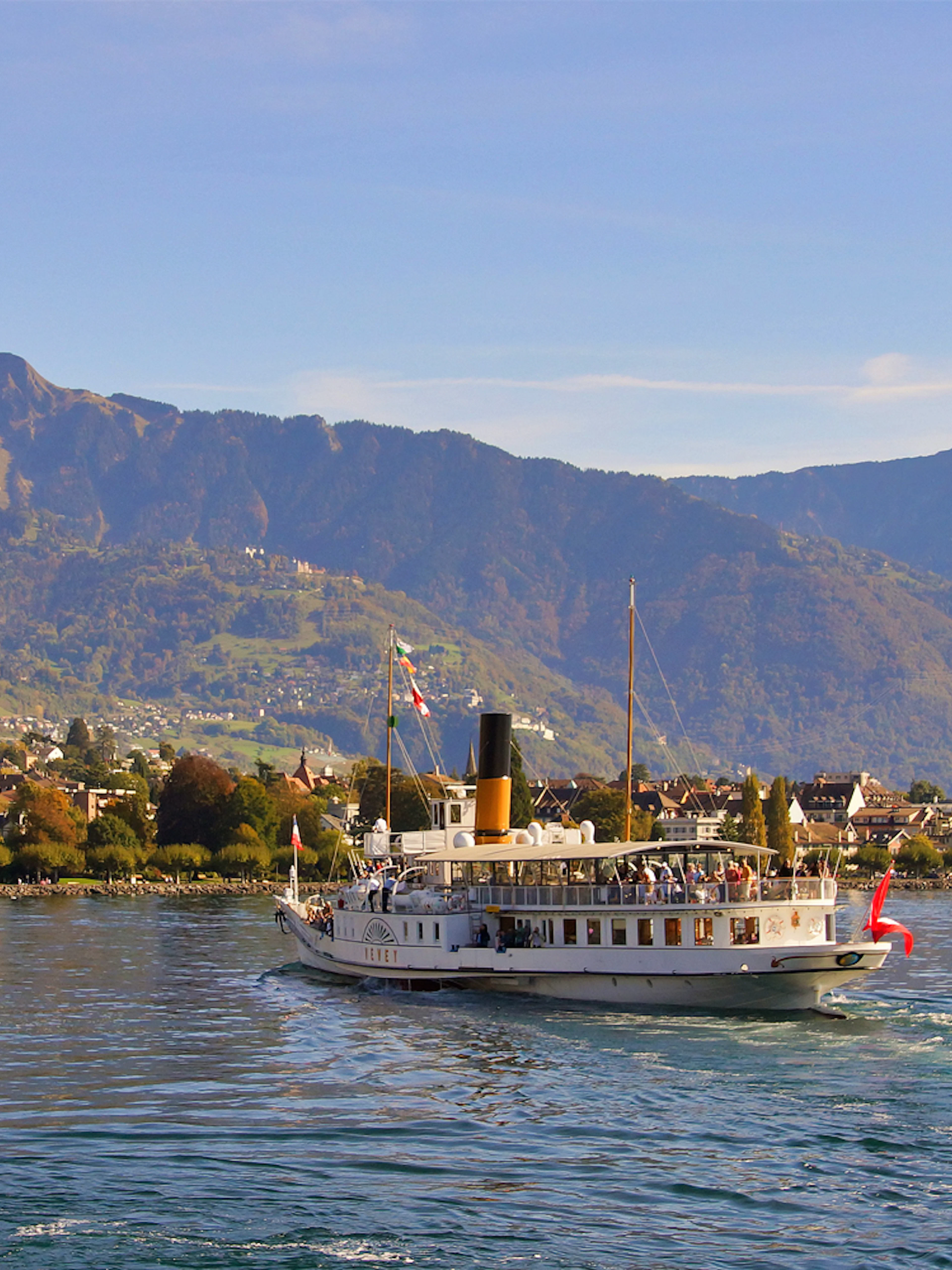 Cruise boat on Lake Geneva with Chillon Castle and mountains in the background, Vevey.