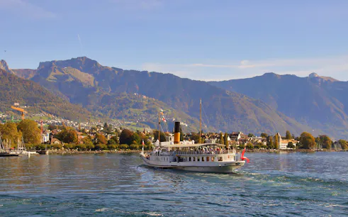 Cruise boat on Lake Geneva with Chillon Castle and mountains in the background, Vevey.