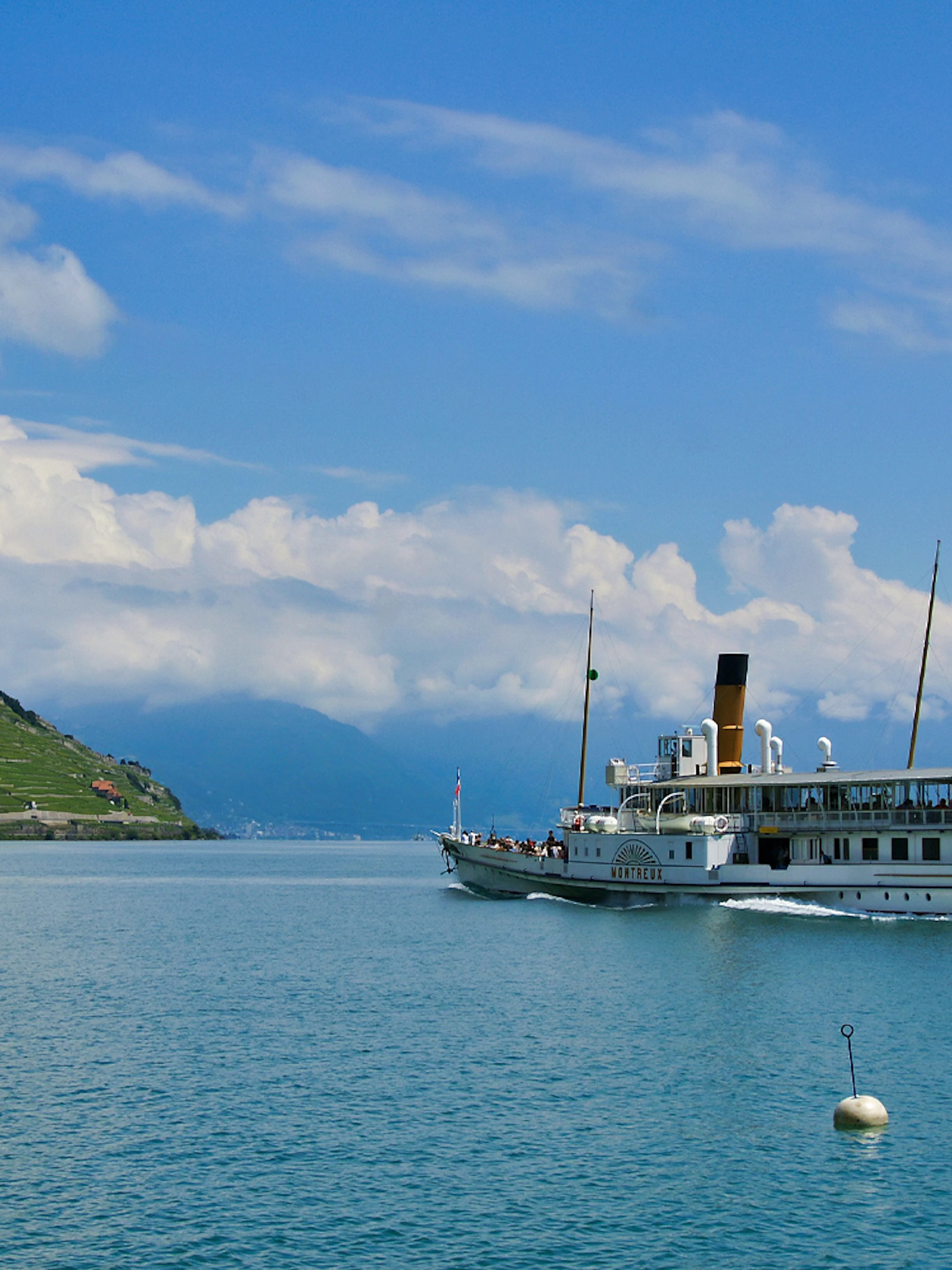 Cruise ship on Lake Geneva with Lavaux vineyards and Swiss flag in view.