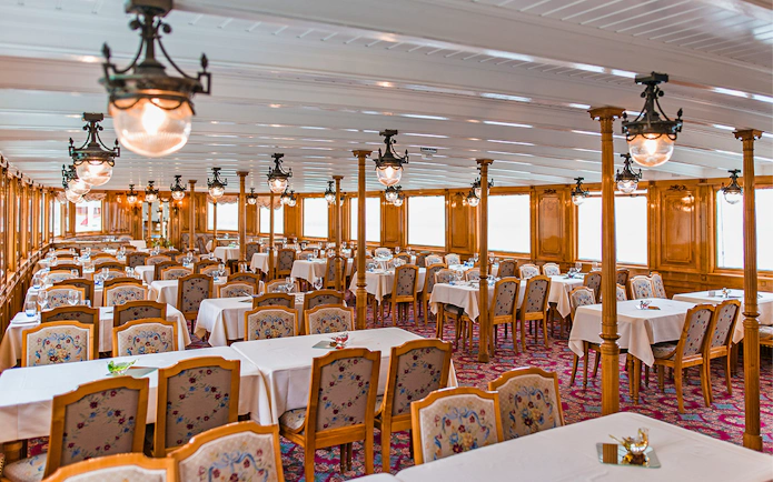 Elegant dining area on a cruise ship in the Riviera region, featuring wooden decor and set tables.