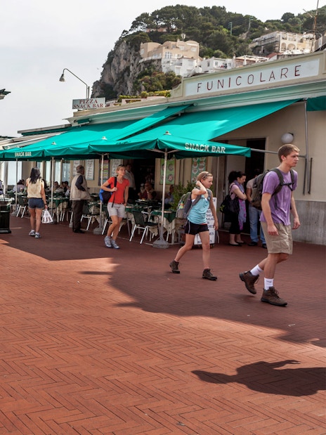 Capri promenade with people relaxing and walking near Funicolare, overlooking the sea.