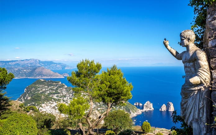 Capri island view with Faraglioni rocks and statue from Naples port tour.