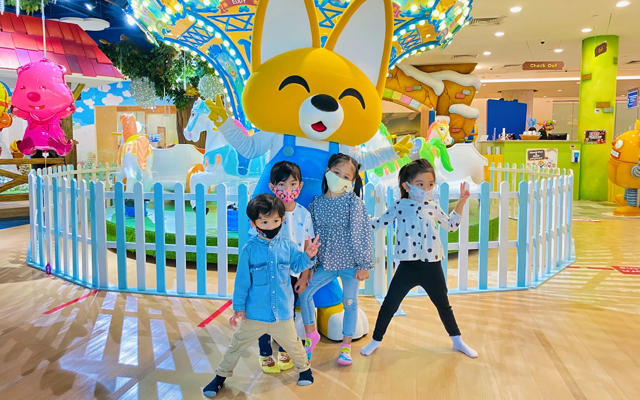 Children posing with a large character statue at Pororo Park indoor playground.
