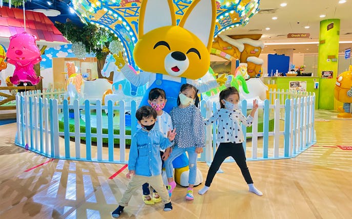 Children posing with a large character statue at Pororo Park indoor playground.