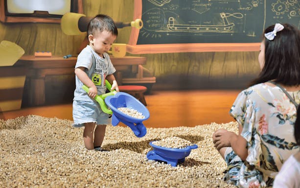 Child playing with toy wheelbarrow at Pororo Park indoor playground.