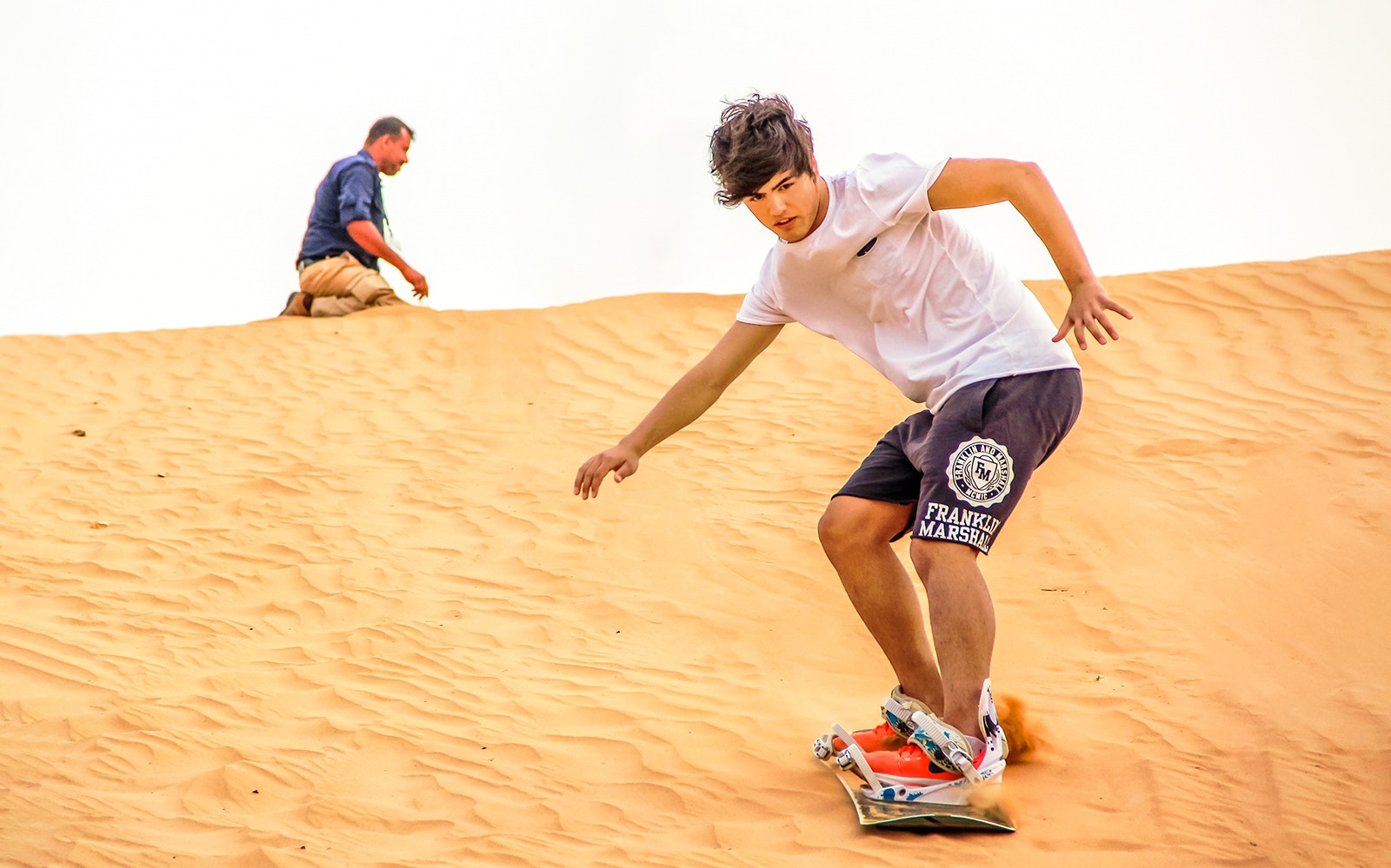 Sandboarding on desert dunes during evening safari experience.