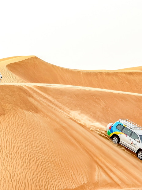 SUVs driving on sand dunes during a desert safari tour.