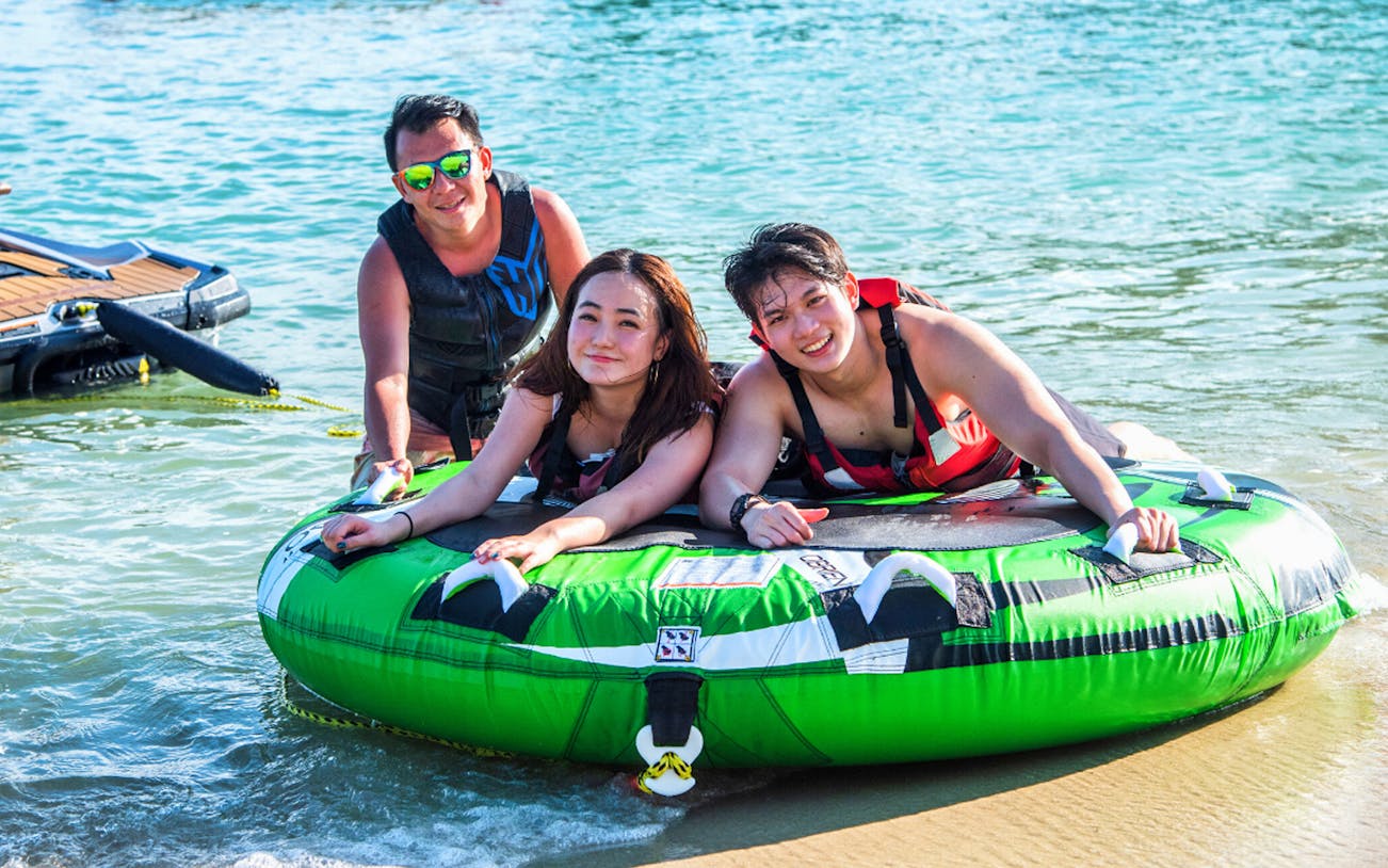 People enjoying a donut ride at Ola Beach Club water activities.