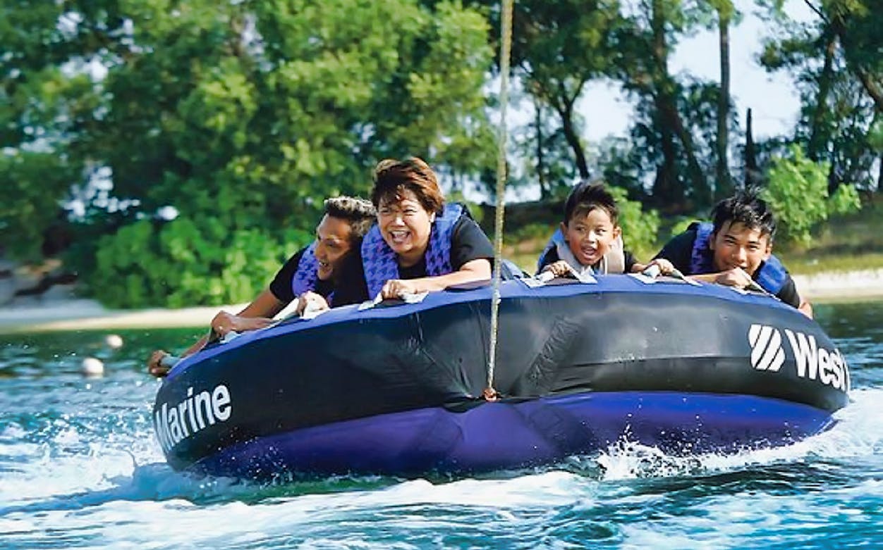 People enjoying a donut ride at Ola Beach Club, Sentosa, Singapore.