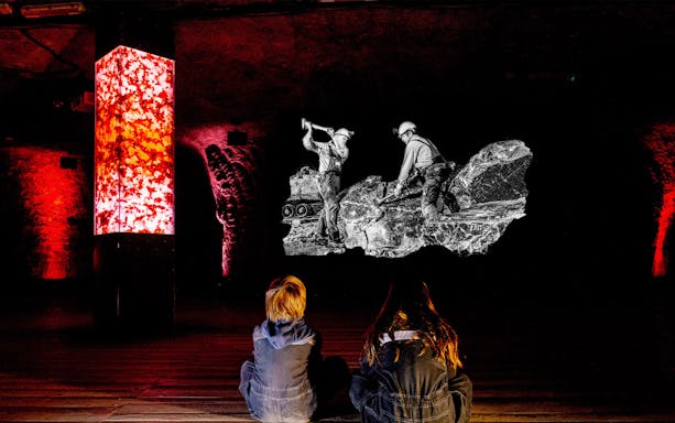 Children watching a salt mine exhibit in Salzburg with illuminated red pillars.