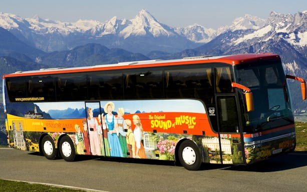 Tour bus for Salzburg Sound of Music and Salt Mines against Alps backdrop.