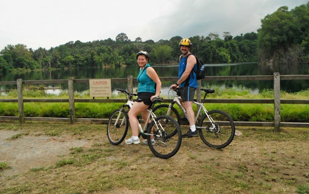 Cyclists on a trail at Pulau Ubin with a scenic lake view.