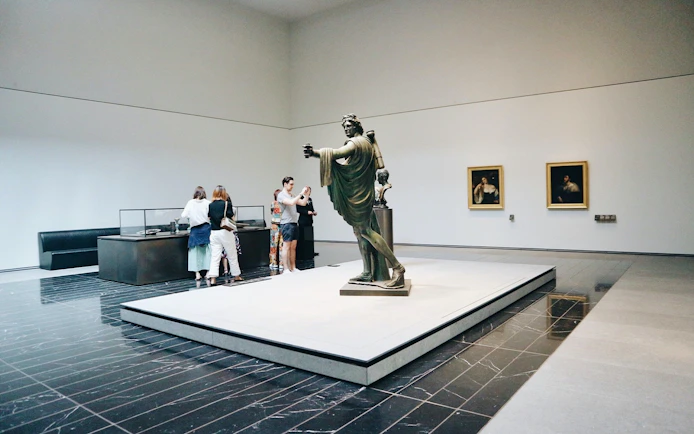 Visitors viewing sculptures and paintings at Louvre Abu Dhabi.
