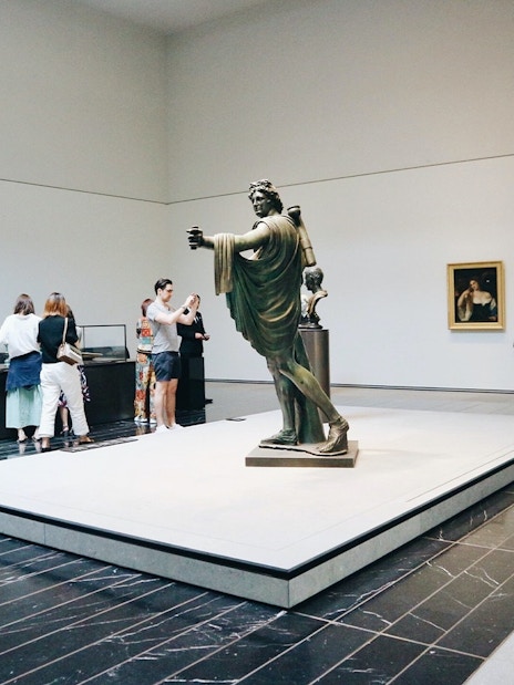 Visitors viewing sculptures and paintings at Louvre Abu Dhabi.