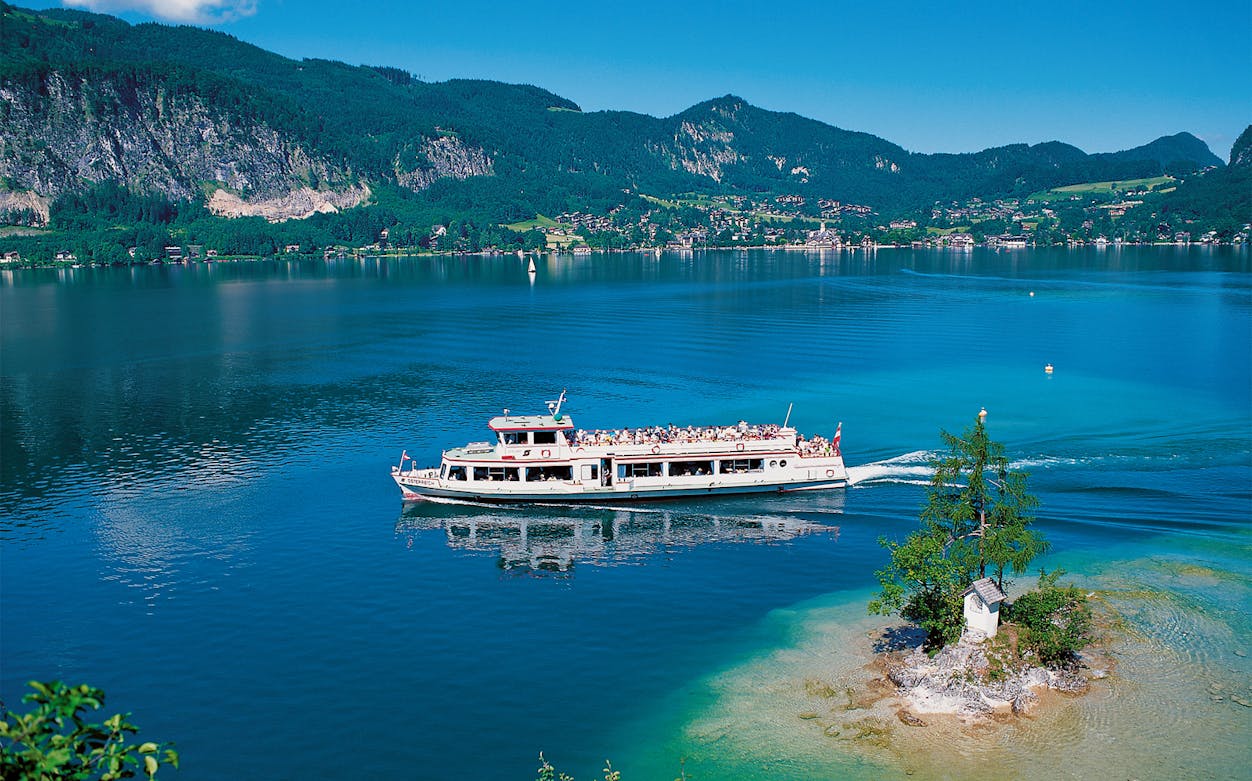 Boat cruising on a lake with mountains in the background, Salzkammergut tour.