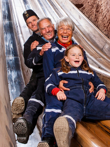 Visitors sliding down wooden chute in Bavarian salt mine, Berchtesgaden tour from Salzburg.