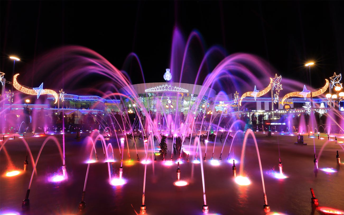 Fountain show with colorful lights at night in SOHO Square, part of the City Tour with Al Mustafa Mosque.