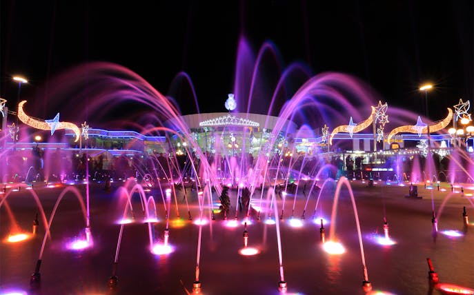 Fountain show with colorful lights at night in SOHO Square, part of the City Tour with Al Mustafa Mosque.