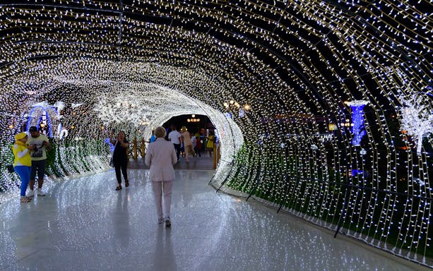 Visitors walking through illuminated tunnel at SOHO Square during city tour.