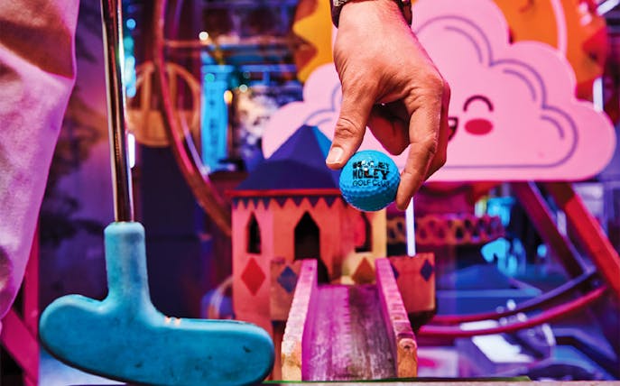 Mini-golf setup at Holey Moley Golf Club with colorful obstacles and a blue golf ball.