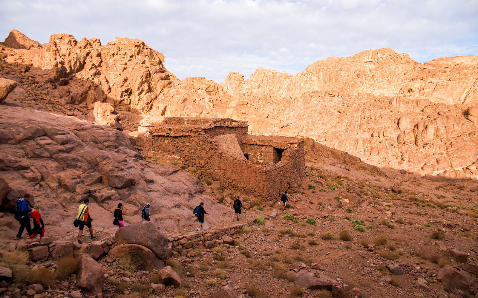 Hikers approaching ancient monastery ruins in Sharm-El-Sheikh desert landscape.