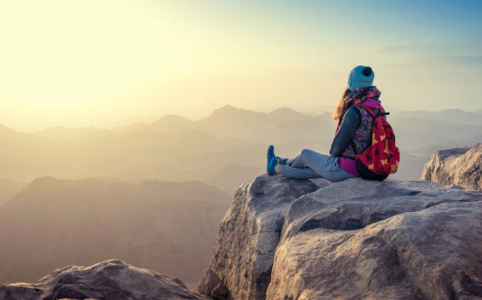 Traveler sitting on a mountain peak at sunrise, Sharm-El-Sheikh hike.