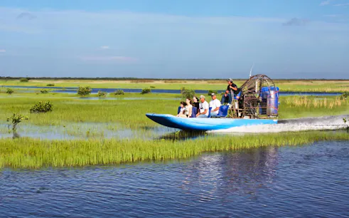Everglades airboat tour with passengers gliding through wetlands.