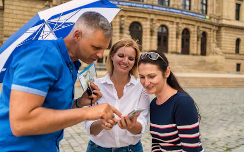 Tourists with guide using phone for Jewish Quarter tour directions.