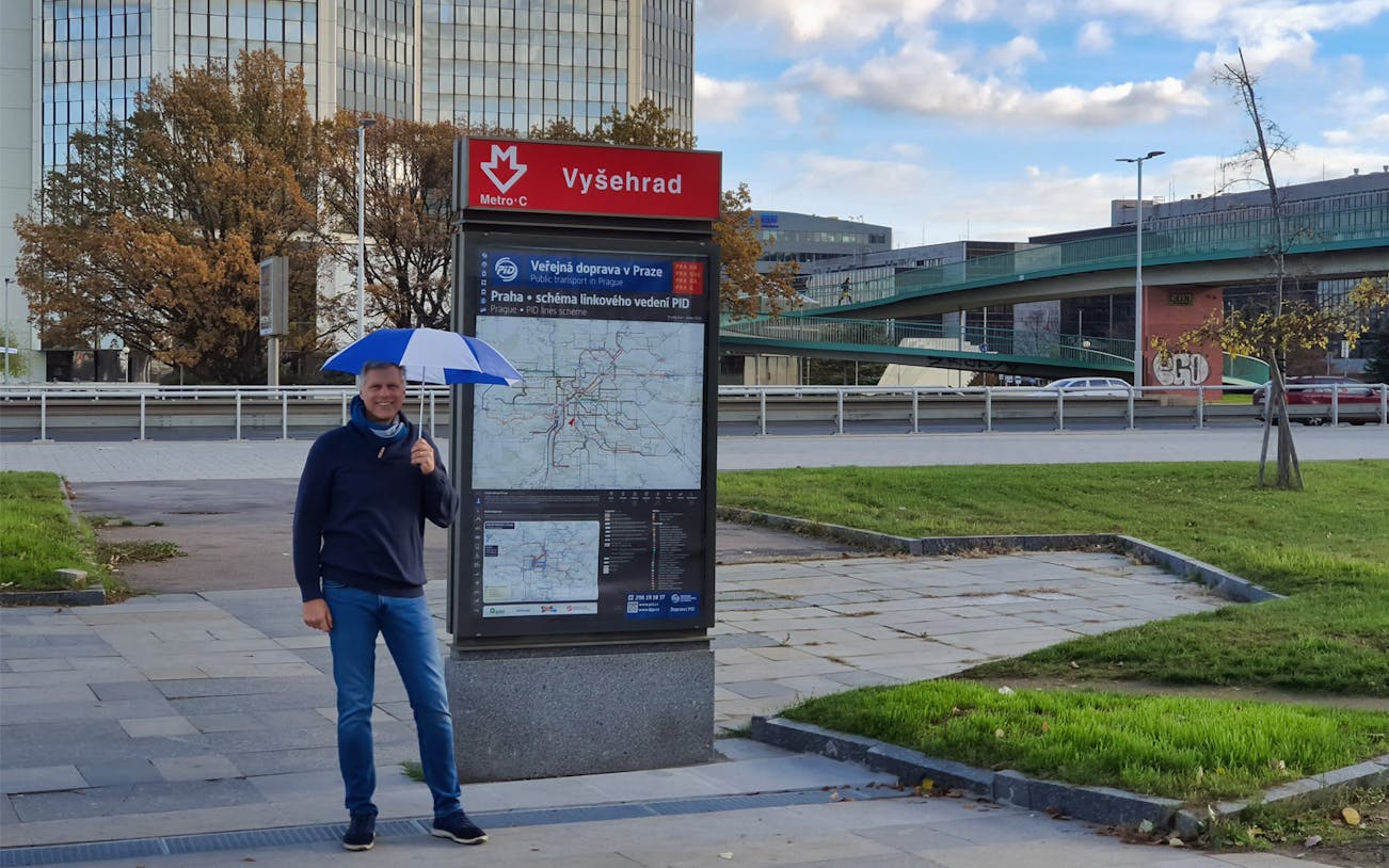 Vyšehrad Metro station entrance in Prague with a man holding an umbrella.