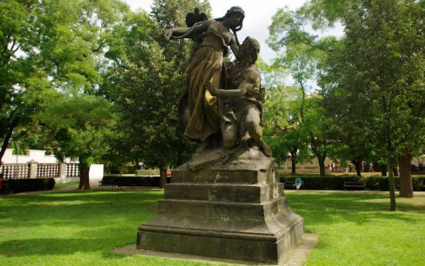 Statue in Vyšehrad Fort park, Prague, surrounded by trees and greenery.