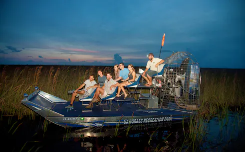 Airboat ride at night through Sawgrass Recreation Park with passengers.