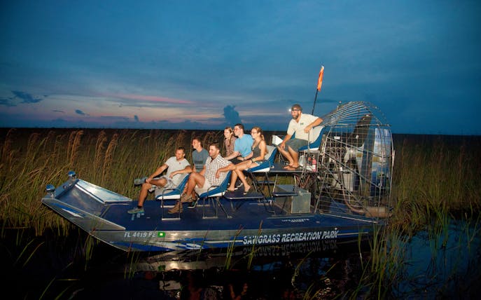 Airboat ride at night through Sawgrass Recreation Park with passengers.