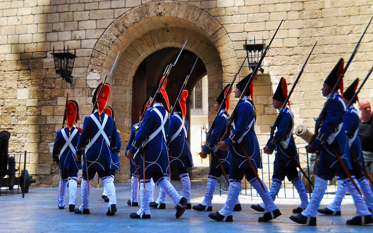 Guards in traditional uniforms marching at Palma's historic site, Mallorca.