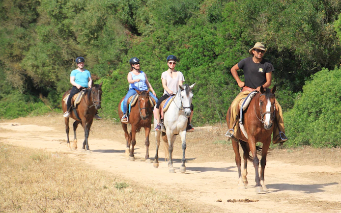 Horseback riders on a sandy trail near the beach in Mallorca.