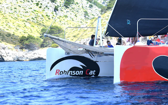 Robinson Catamaran sailing in Pollensa Bay with passengers enjoying the view.