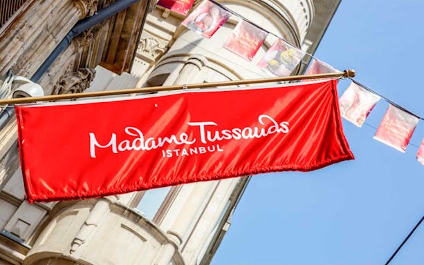 Madame Tussauds Istanbul entrance sign with red banner against building facade.