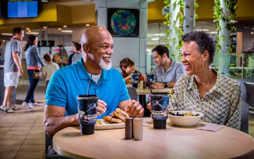 Couple enjoying a meal at Kennedy Space Center cafe during guided tour.