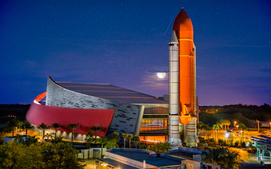 Kennedy Space Center rocket display at night with illuminated building.