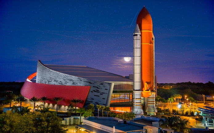 Kennedy Space Center rocket display at night with illuminated building.