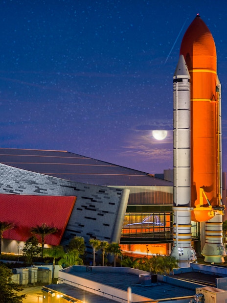 Kennedy Space Center rocket display at night with illuminated building.
