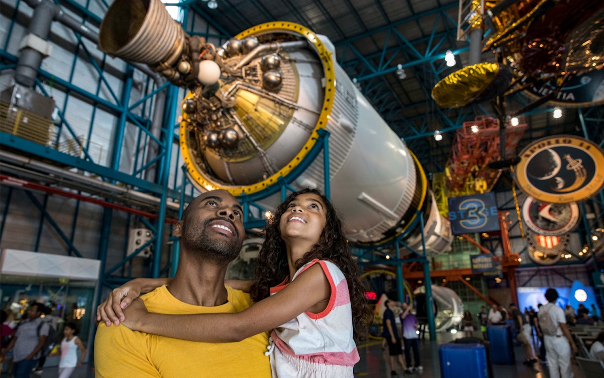 Father and daughter admiring a rocket at Kennedy Space Center, Florida.