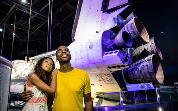 Visitors admiring a space shuttle at Kennedy Space Center, part of the ICON Park tour.