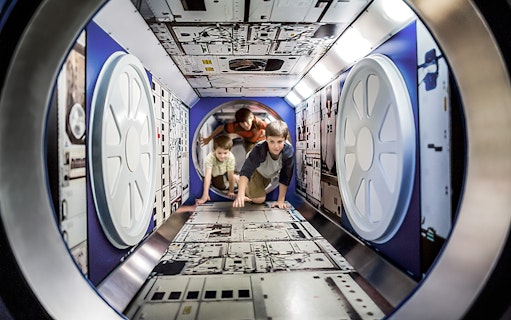 Children exploring a space module exhibit at Kennedy Space Centre.
