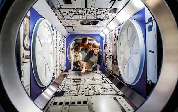 Children exploring a space module exhibit at Kennedy Space Centre.