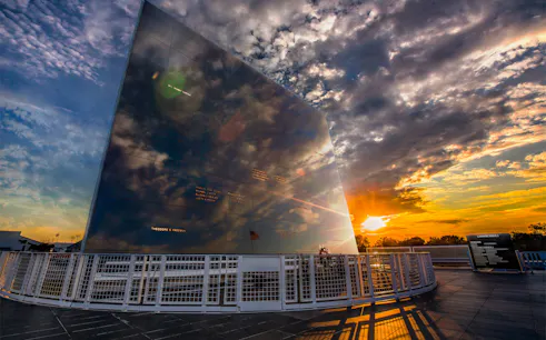 Kennedy Space Center memorial wall at sunset reflecting clouds and sky.